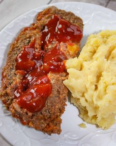 meatloaf, mashed potatoes and gravy are on a white plate