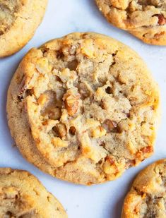 several cookies with nuts and crumbles sitting on top of a white countertop