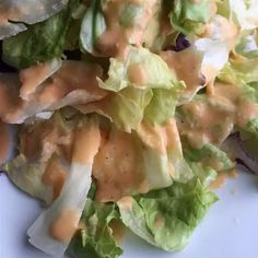 lettuce with dressing on it is sitting on a white plate and ready to be eaten