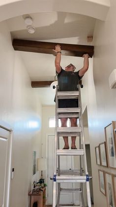 a man is standing on a ladder and reaching up to the ceiling