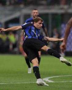 a man kicking a soccer ball on top of a field