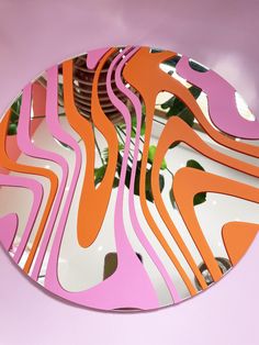 a mirror that is on top of a pink wall with an orange and white design