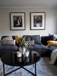 a living room filled with furniture and two pictures on the wall above it's coffee table