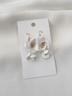 two white flowers with gold centers are on a card for the earring to be worn