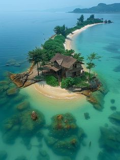 an island with a house on it in the middle of clear blue water and sand