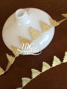 a white plate topped with gold foil christmas trees on top of a wooden table next to a cup