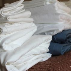 a pile of folded clothes sitting on top of a bed