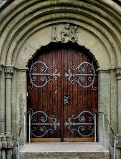 an old church door with wrought iron work on the front and side steps leading up to it