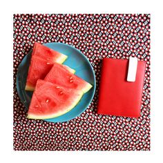 watermelon slices on a blue plate next to a red notebook