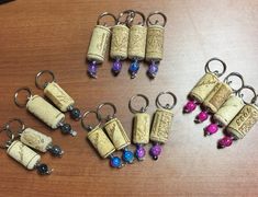 several wine corks with charms attached to them sitting on a wooden table next to each other