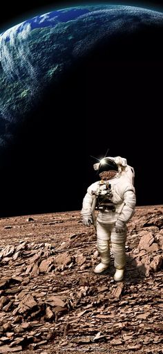 an astronaut standing on the ground in front of a large blue planet with rocky terrain