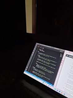 an open laptop computer sitting on top of a desk in front of a dark wall