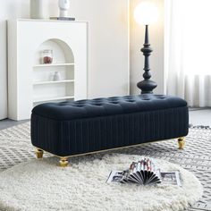 a black bench sitting on top of a rug next to a white book shelf and lamp