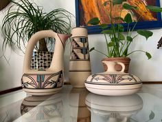 three vases sitting on top of a glass table next to a potted plant