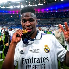 a soccer player holding up his medal in front of the crowd