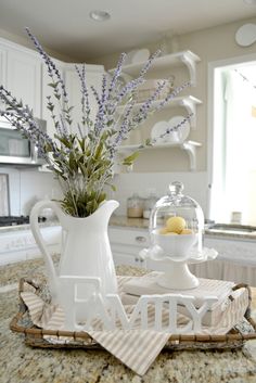 a white pitcher with lavenders in it sitting on a tray