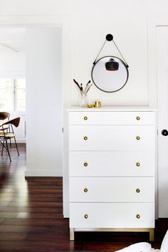 a white dresser with gold pulls and brass knobs on the bottom, is featured in this article