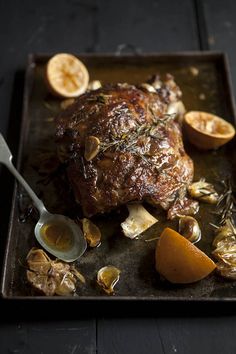 a roasting pan with meat, potatoes and oranges on it for garnish