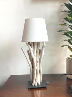 a lamp made out of driftwood on a table next to a potted plant