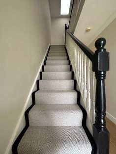 a staircase with white carpet and black handrails