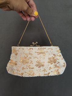 "This is such a unique bag! Made by hand in the 40s in Japan for Schildkraut Bros. It is a beautiful gold floral brocade with white small beads to accentuate and enhance floral details throughout. Gold chain handle with gold closure and rhinestones at top of gold closure snaps gives it that special something every time it's opened. Gold silk interior lining has some black ink stains throughout but the exterior is in perfect condition.  Measurements Length 10\" height 5\" depth 1 1/2\"" Elegant Beige Bag For Vintage Events, Vintage Wedding Bags With Gold Embroidery, Gold Rectangular Evening Bag With Pearl Embroidery, Gold Evening Bag With Pearl Embroidery For Formal Occasions, Formal Gold Clutch With Pearl Embroidery, Elegant Wedding Bag With Gold Beads, Vintage Beige Evening Bag With Pearl Handle, Gold Clutch With Pearl Embroidery For Evening, Vintage Gold Embroidered Clutch