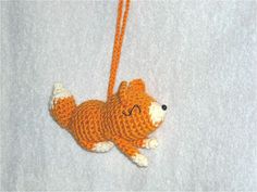 an orange and white stuffed animal hanging from a string on a white surface with the tag attached to it