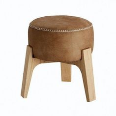 a small stool with wooden legs and a brown leather cushion on the top, sitting in front of a white background