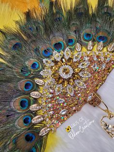 Oshun inspired golden peacock hand fan. Peacock feathers, ostrich feathers with golden cowrie shells, yellow crystal sun, sparkle, jewels and charms. Each item is respectfully made with the highest quality materials. Please note: All items are made to order and ship within 4-6 weeks! Style may slightly vary due to material availability. For custom color ... Peacock Accessories, Golden Peacock, Nigerian Dress, Womb Healing, Couture Hats, Cowrie Shells, Goddess Of Love, Peacock Feathers, Ostrich Feathers