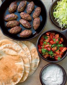 the meal is prepared and ready to be eaten with pita bread, tomatoes, lettuce