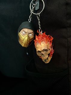 two key chains hanging from the back of a backpack with a skull on it's face