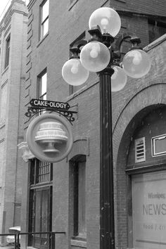 an old fashioned street light in front of a brick building with a sign on it