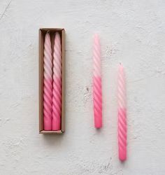 three pink candles sitting in a box next to each other on a white wall background