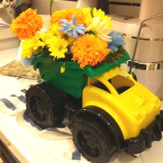 a yellow toy truck with flowers in it