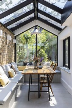 a room with a table, couches and windows in the ceiling is lit by an outdoor light