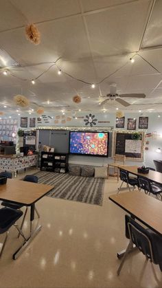 an empty classroom with desks, chairs and a flat screen tv on the wall