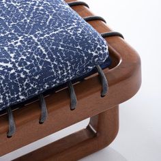 a blue and white cushion sitting on top of a wooden chair with metal ties around it