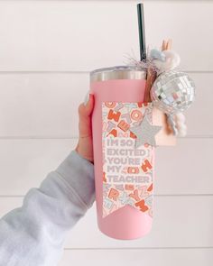 a person holding up a pink cup with a straw in it and a star decoration on the top