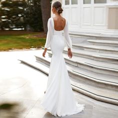 a woman in a white wedding dress standing on some steps with her back to the camera