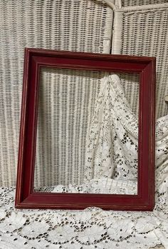 a red frame sitting on top of a bed next to a white lace covered wall