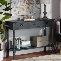 a black console table with two drawers and a lamp on the top, in front of a painting