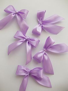 four purple bows are arranged on a white surface