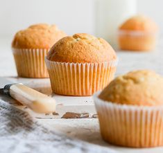 three muffins sitting on top of a table next to a knife