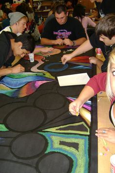 a group of young people sitting at a table working on artwork