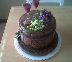 a chocolate cake with grapes and wine glasses on top