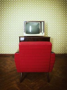 an old television sitting on top of a red chair