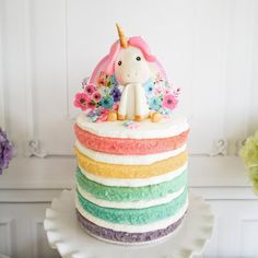 there is a cake that looks like a unicorn on top of it with flowers in the background