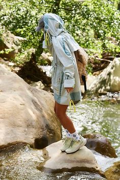 a woman standing on top of a rock next to a river