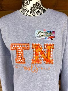 "Uniquely embroidered raw edge varsity appliqué letters of TN for the great state of Tennessee.  Made in layers of coordinating fabrics 3.5\"tall Letters & vols motto embroidered under.  Each shirt is unique as fabrics may vary. The raw edge APplique will allow the fabrics to fray a bit with each wash.  These are a great way to show school / state spirit.  I have added a Denim Shirt option that will include the featured design in a Chest Embroidery. PLEASE NOTE your information when ordering   Fabric styles, and patterns will vary depending on types available ** Check out our Facebook page  https://www.facebook.com/Needle-Nut-Embroidery-100913691324151/" Fall College T-shirt With Embroidered Graphics, Varsity T-shirt With Embroidered Graphics For Fall, Collegiate Tops With Embroidered Graphics For College, Embroidered Fall College T-shirt, Embroidered Graphics T-shirt For College In Fall, Varsity T-shirt With Letter Embroidery For College, Embroidered Fall College Top, Varsity T-shirt With Letter Embroidery, Fall College Top With Embroidered Graphics