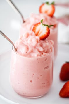 two strawberry milkshakes on a white plate with strawberries