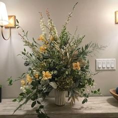 a vase filled with yellow flowers sitting on top of a table next to a lamp